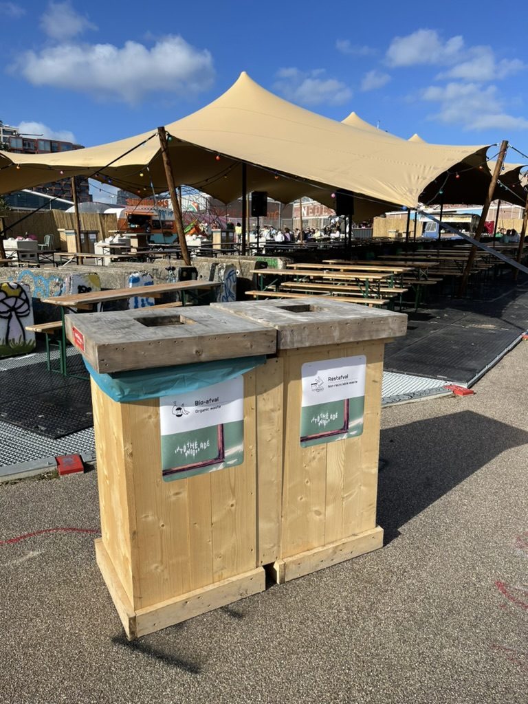 Houten afvalbakken met een label per stroom op het terrein van ADE