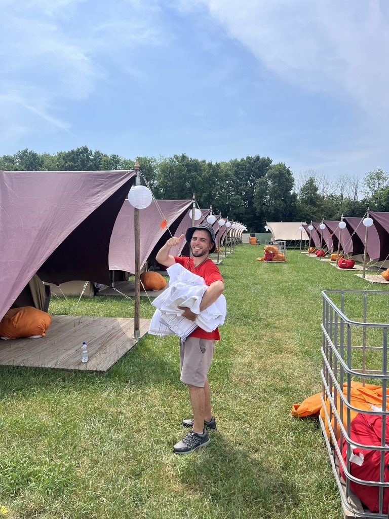 Collega met een stapel schoon beddengoed tussen de glampingtenten
