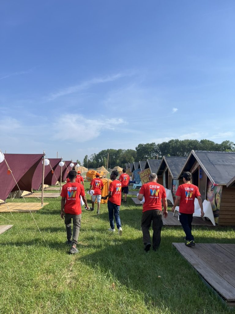 Onze crew loopt in bedrijfskleding tussen de tenten op een festivalcamping