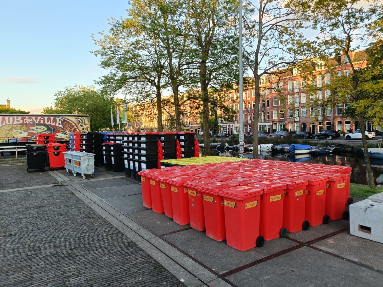 Tientallen rode rolcontainers klaargezet langs een gracht voor een evenement in de stad